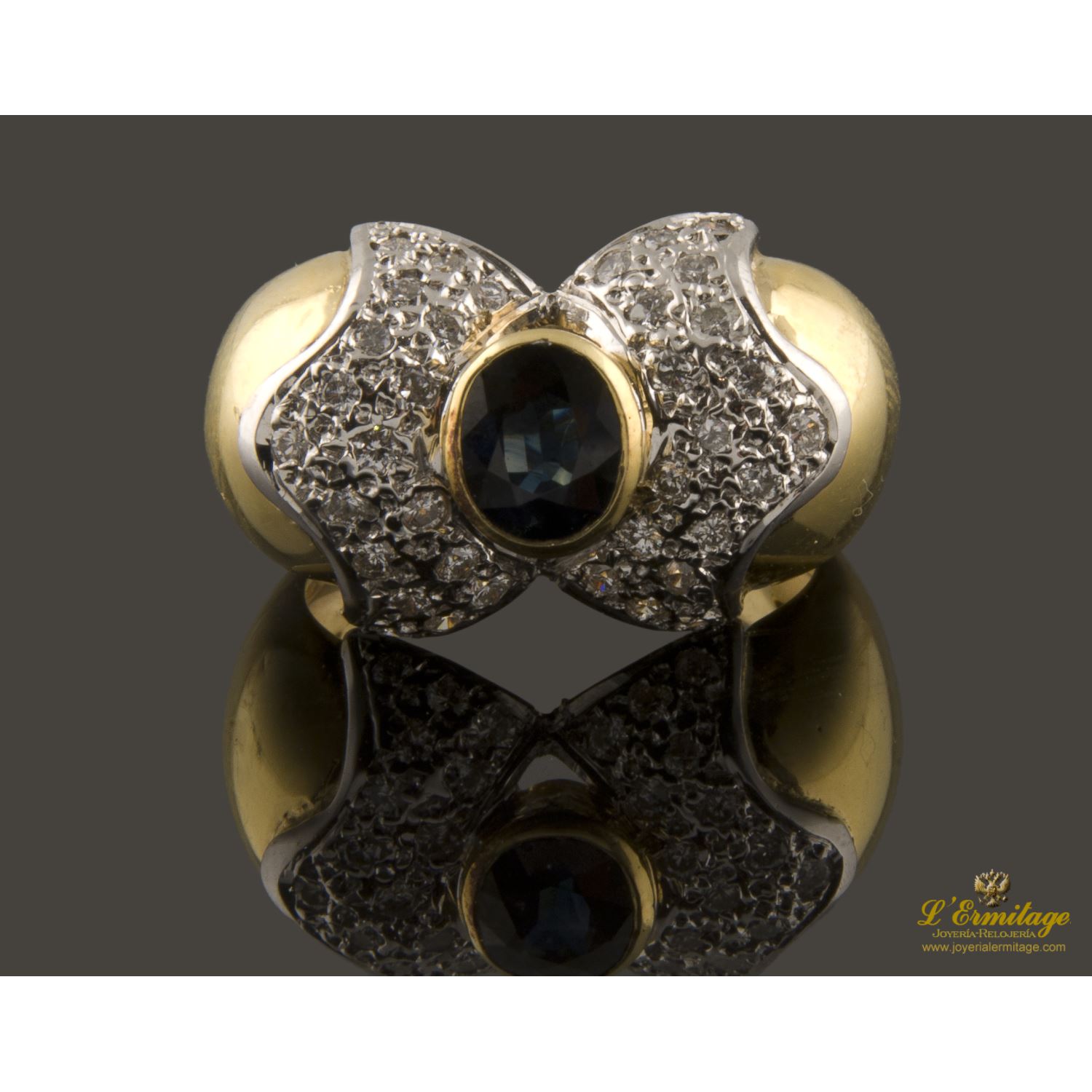 Presenta un zafiro natural central talla oval y cuajado de brillantes