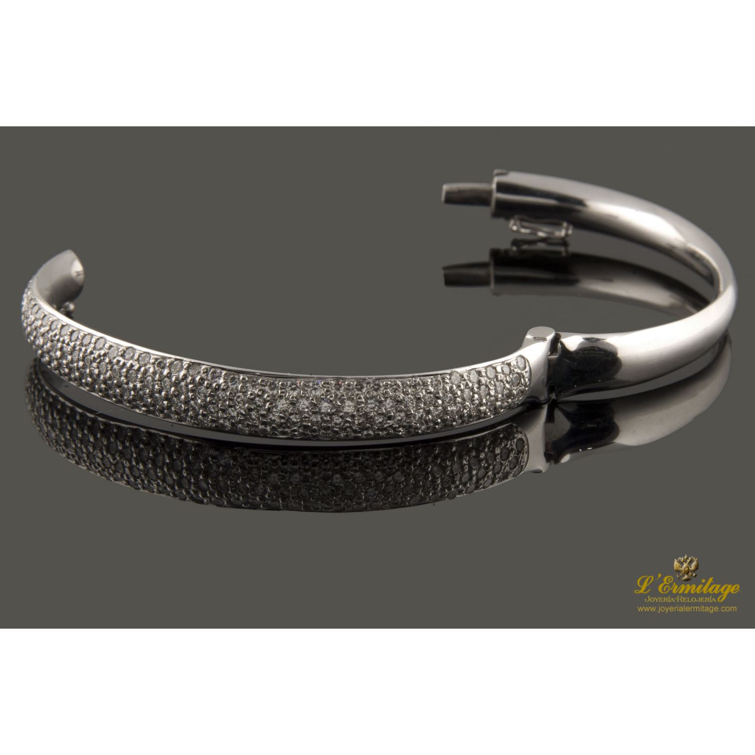 Pulsera rígida de media caña con centro pabe de brillantes montados en oro blanco.